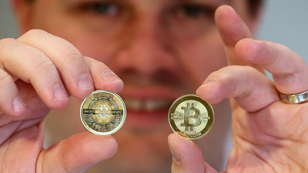 Ahli perangkat lunak, Mike Caldwell memperlihatkan bagian depan dan belakang sebuah Bitcoin fisik di tokonya yang berlokasi di Sandy, Utah. (AFP Photo / George Frey)